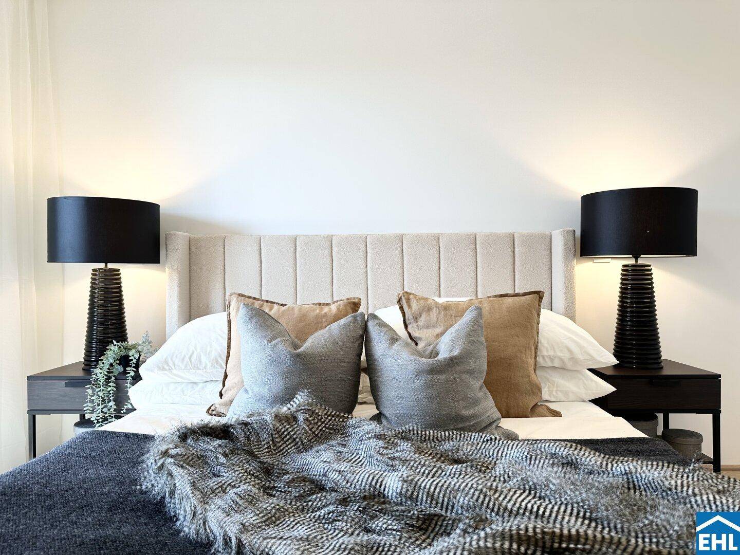 Detailansicht eines Schlafzimmers mit großem Bett, bequemen Kissen und Nachttischlampen.