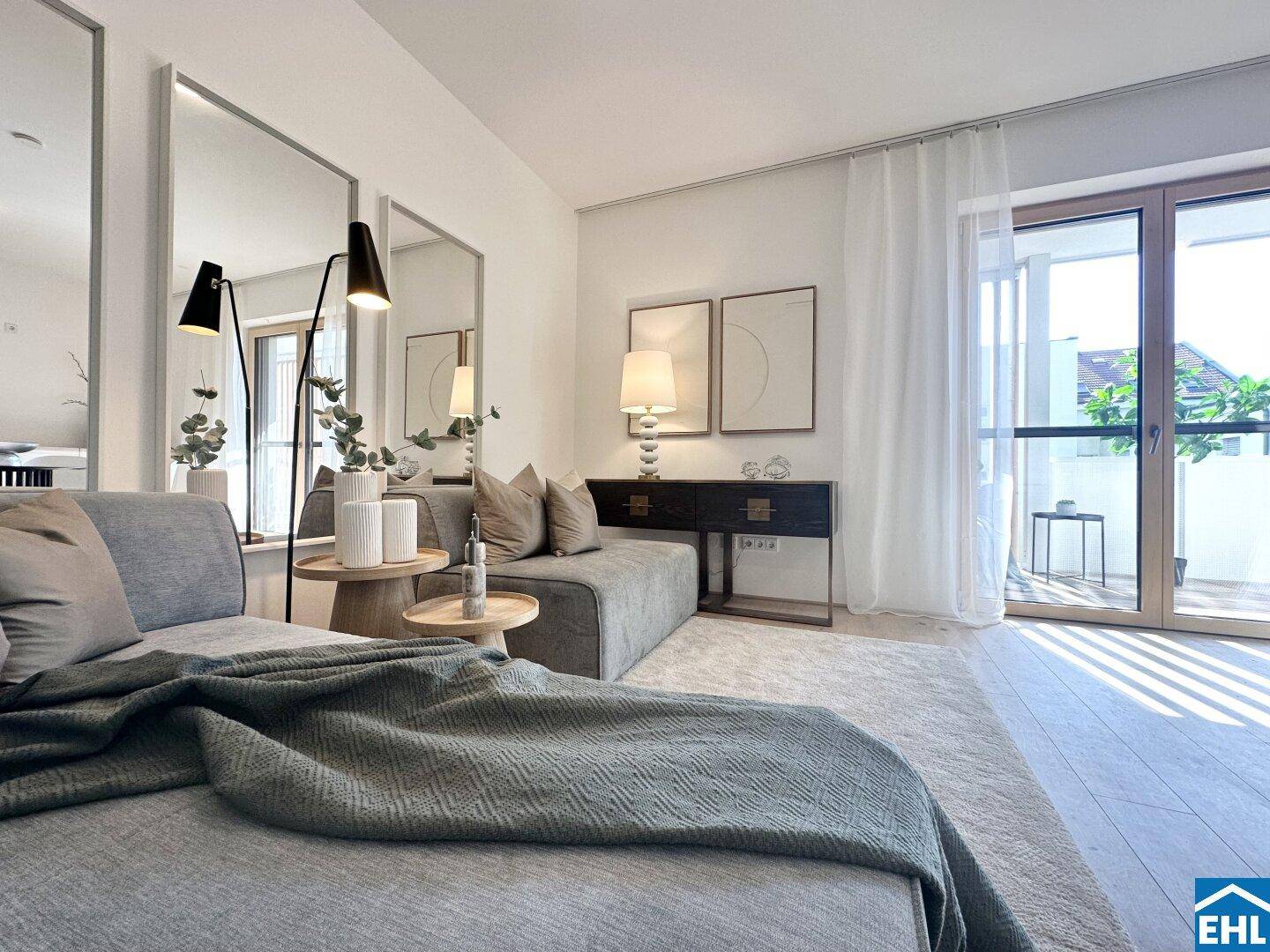 Heller Wohnbereich mit Zugang zum Balkon, großen Fenstern und modernen Möbeln.