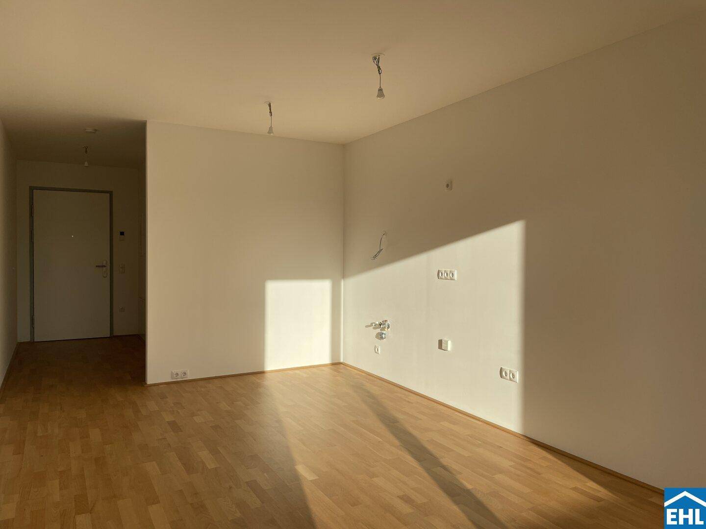 Geräumiger, leerer Raum mit Parkettboden und viel Sonnenlicht, bereit für individuelle Gestaltung.
