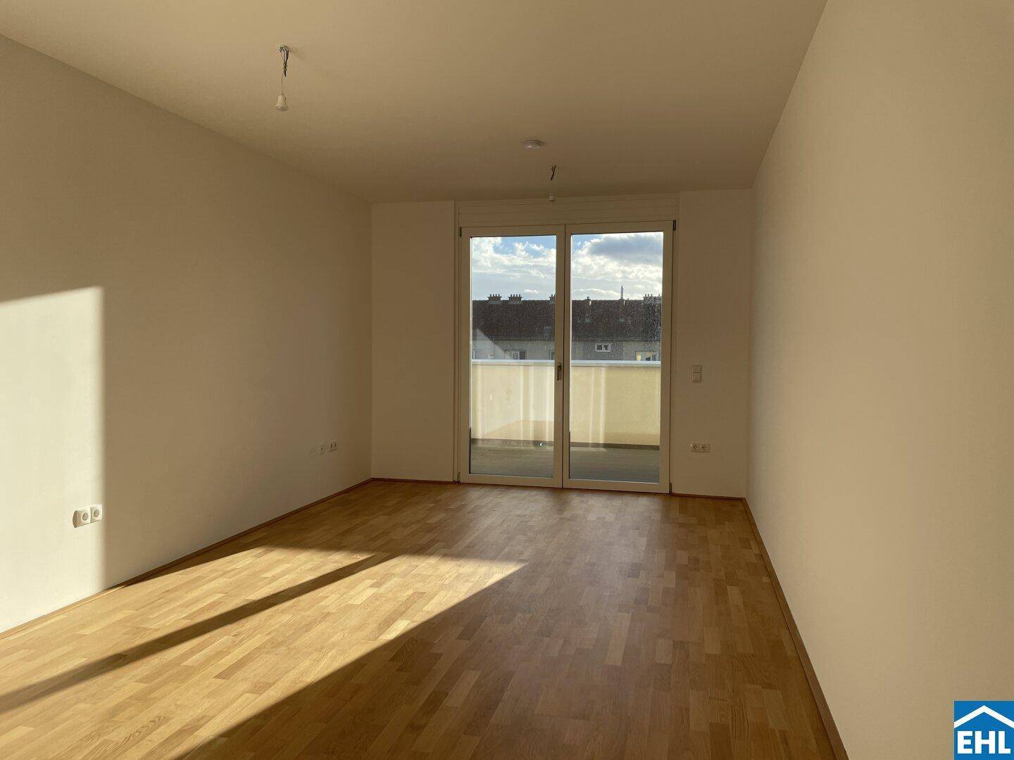 Heller Wohnbereich mit Parkettboden und direktem Zugang zum Balkon.
