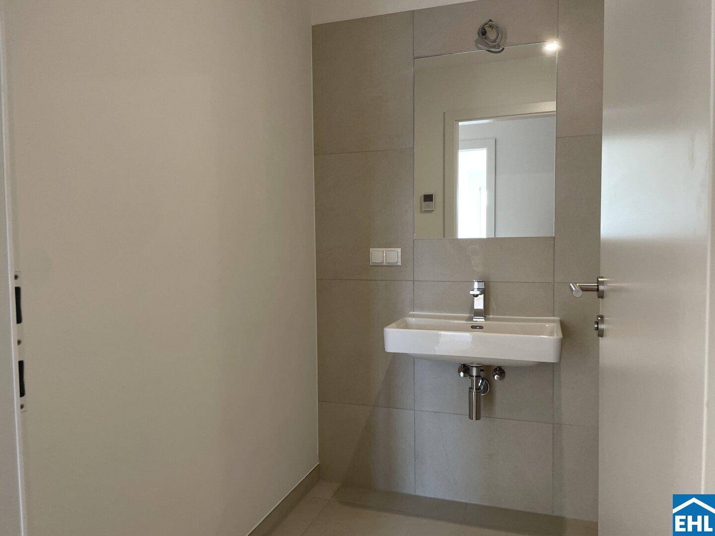 Modernes Badezimmer mit Fliesen, einem einzelnen Waschbecken und großem Spiegel.