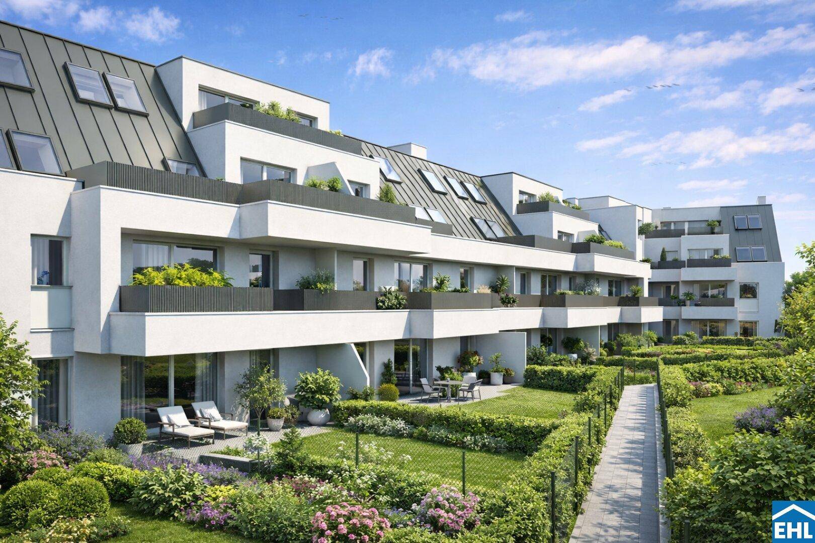 Moderne Wohnanlage mit Terrassen, Gärten und gepflegten Grünflächen unter blauem Himmel.