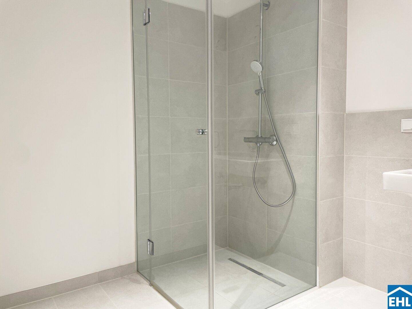 Geräumige, begehbare Dusche mit Glaswänden und modernen Armaturen in einem hellen Badezimmer.