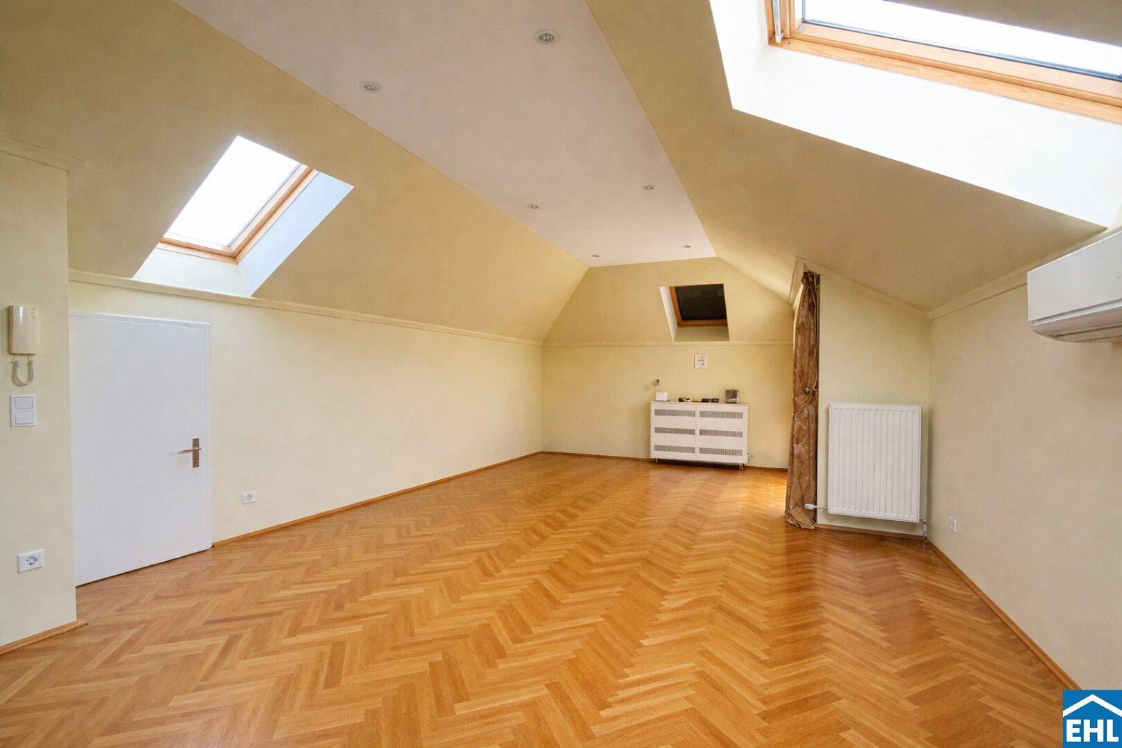 Helles Dachgeschosszimmer mit Parkettboden, mehreren Dachfenstern und Klimaanlage für angenehmes Klima.