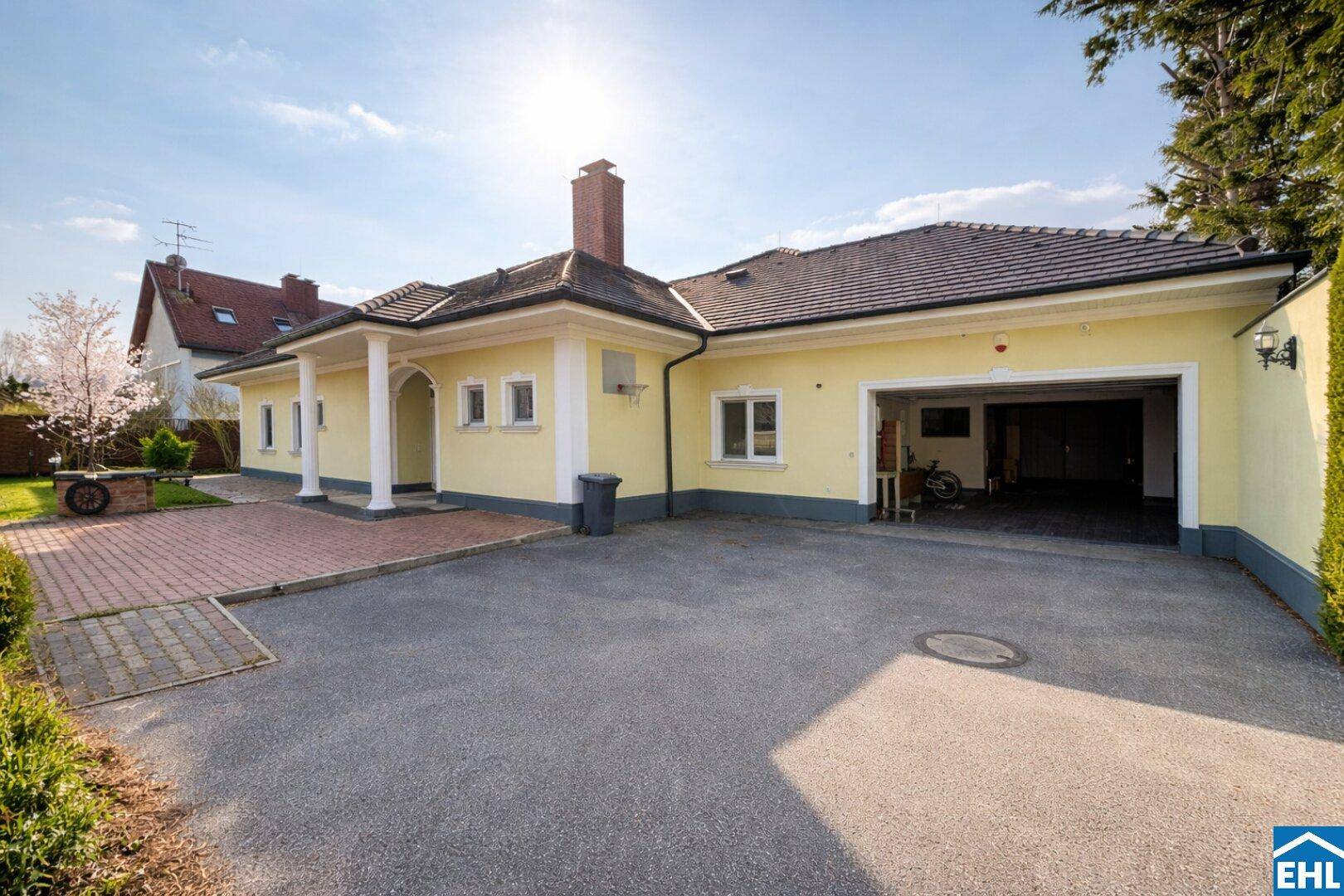 Hausfassade mit großer Einfahrt, integrierter Garage und Säulen am Eingangsbereich.