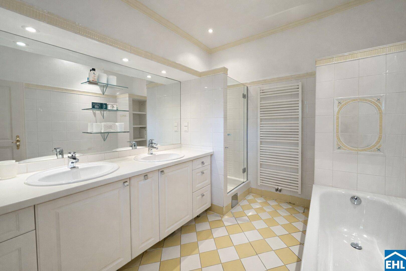 Geräumiges Badezimmer mit Doppelwaschbecken, Badewanne und Duschbereich, hell gefliest.