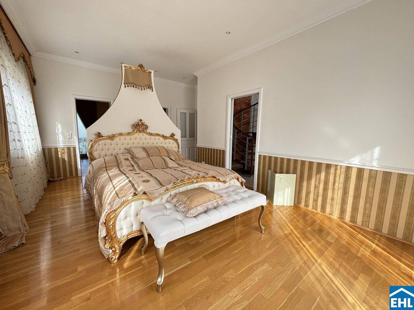 Luxuriöses Schlafzimmer mit großem Himmelbett, Parkettboden und Zugang zur Wendeltreppe.