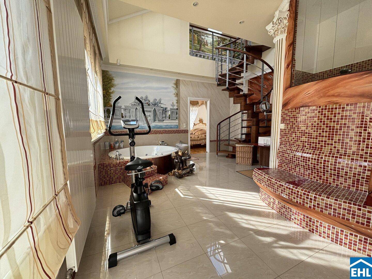 Wellnessbereich mit Whirlpool, Trainingsgerät und Wendeltreppe, ideal zur Entspannung und Fitness.