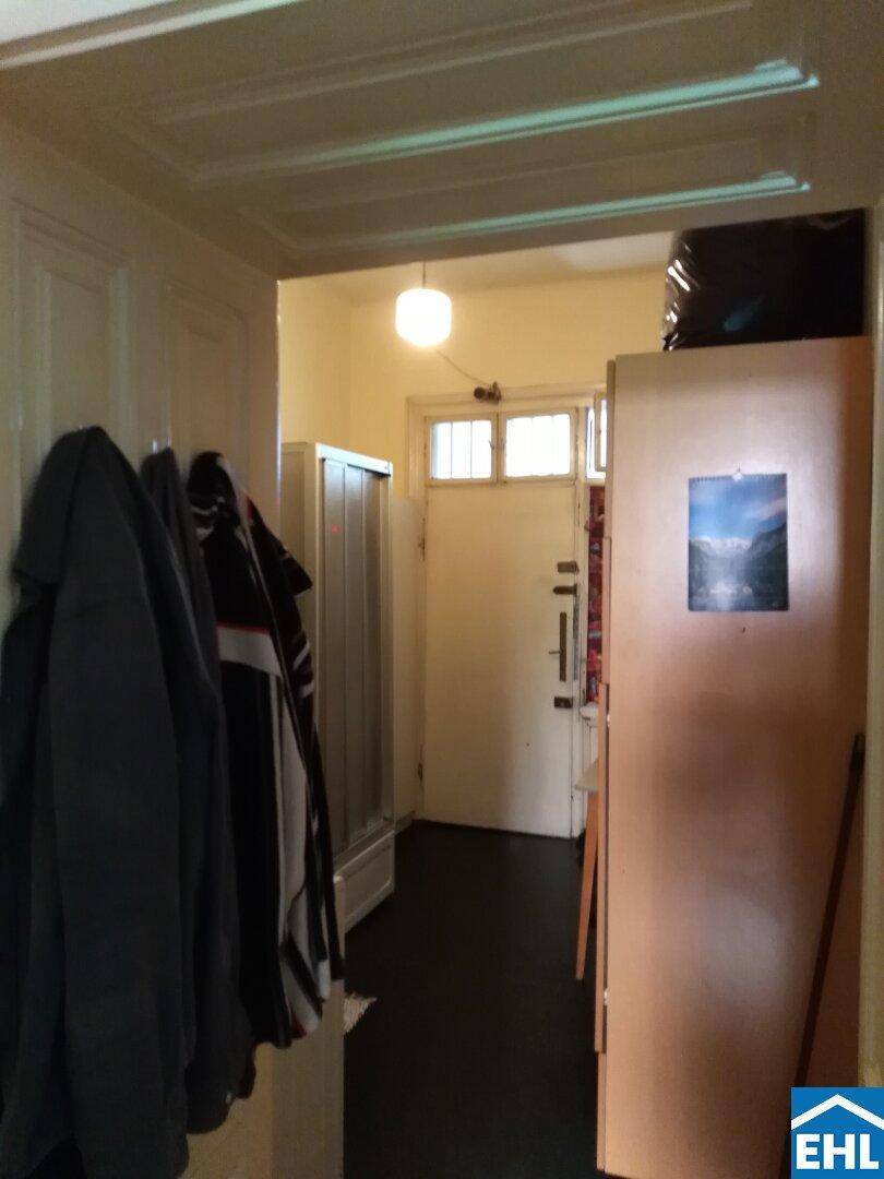 Eingangsbereich mit dunklem Boden und Garderobe, der zu den weiteren Räumen führt.