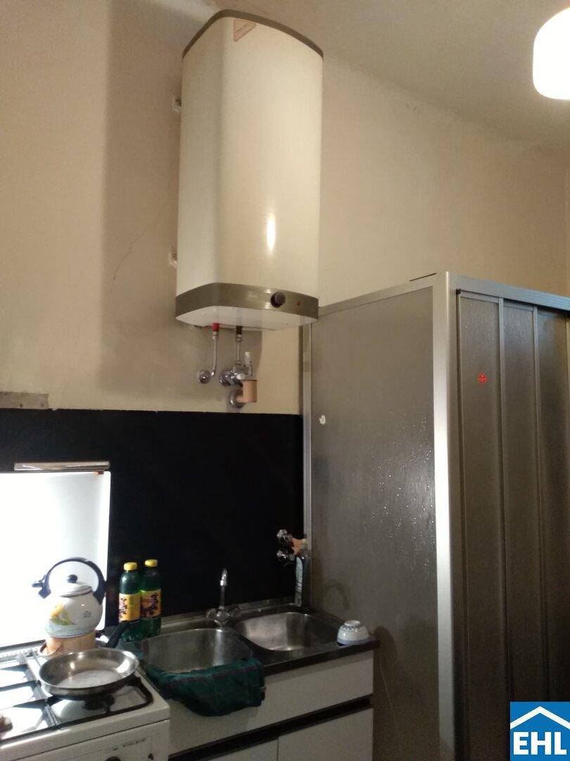 Kleine Küche mit Spüle, Herd und Warmwasserboiler, funktional eingerichtet für den täglichen Gebrauch.