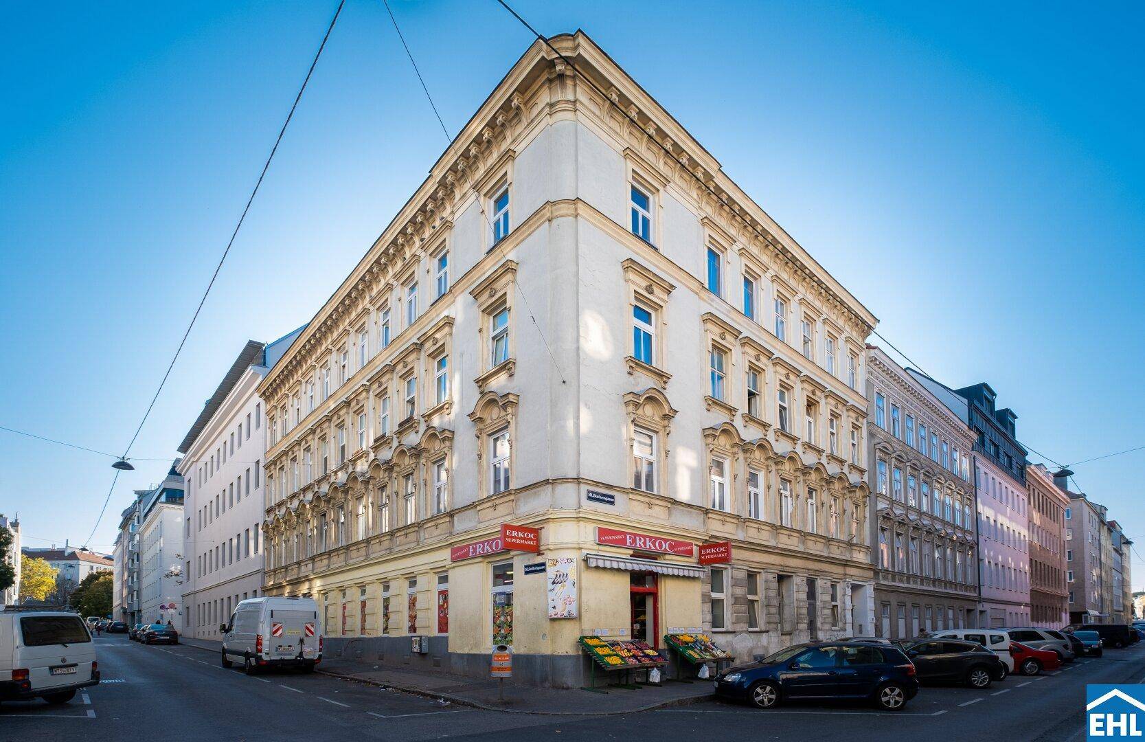 Eckgebäude mit historischer Architektur und Geschäften im Erdgeschoss an einer städtischen Kreuzung.