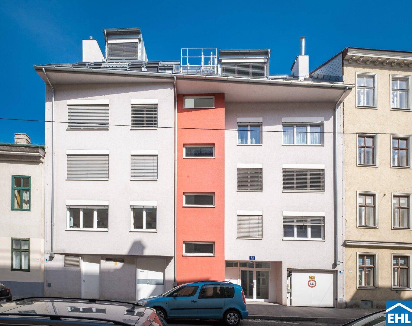 Moderne Gebäudefassade mit weißen Jalousien und einem auffälligen orangefarbenen Akzent.