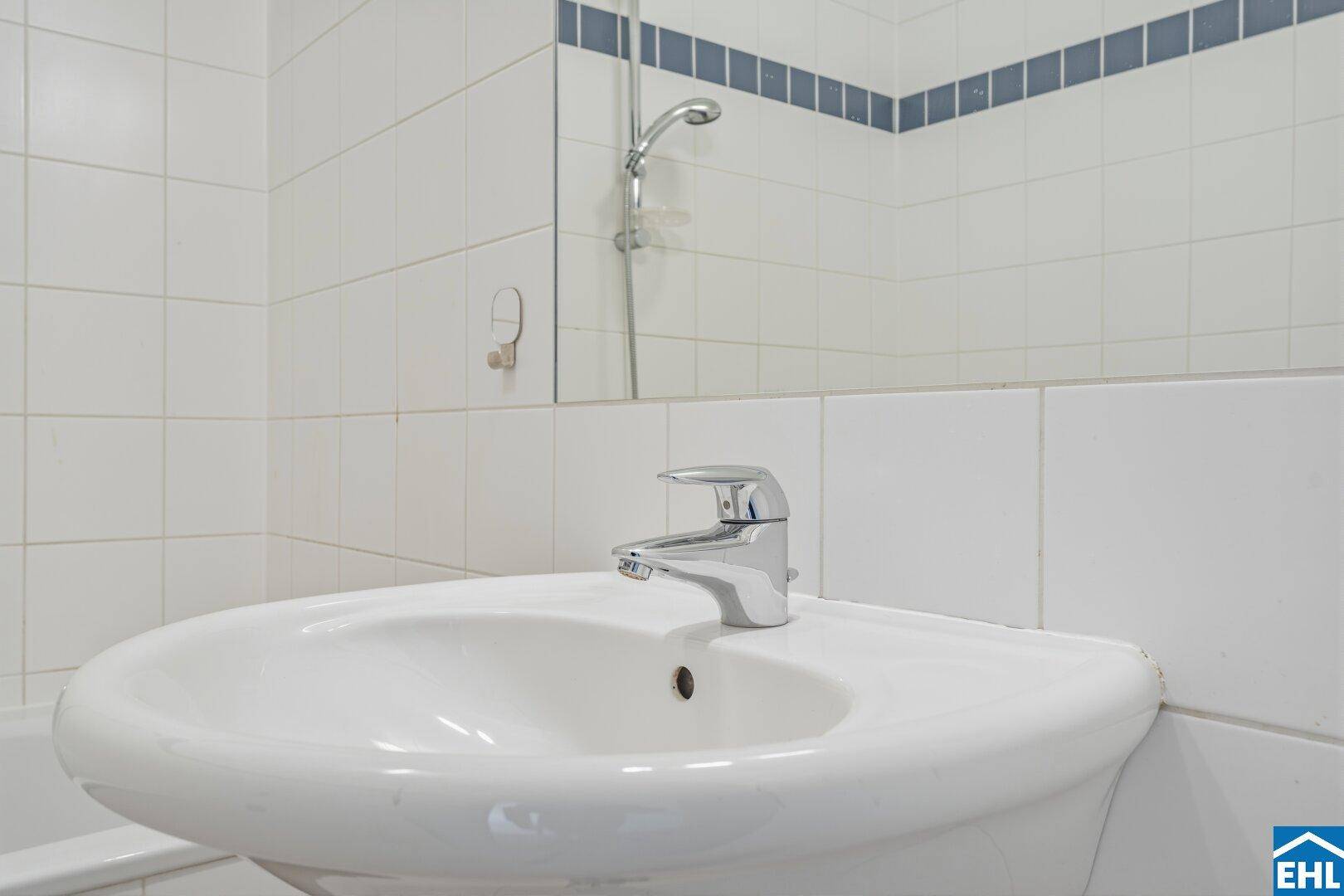 Waschbecken mit modernem Wasserhahn in einem gefliesten Badezimmer.