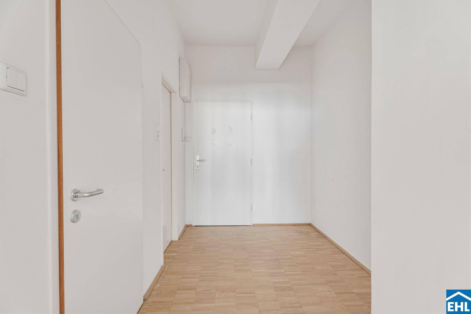 Heller Flur mit Parkettboden und weißen Türen.