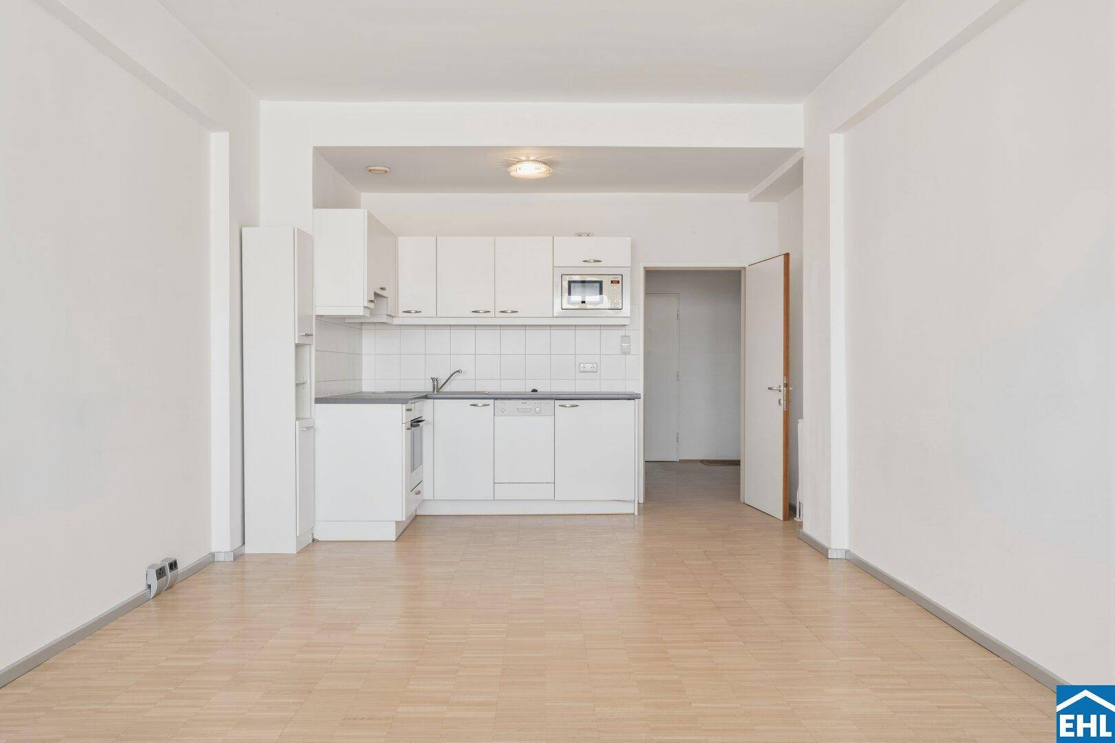 Funktionale weiße Küchenzeile mit Backofen, Mikrowelle und Spülmaschine.