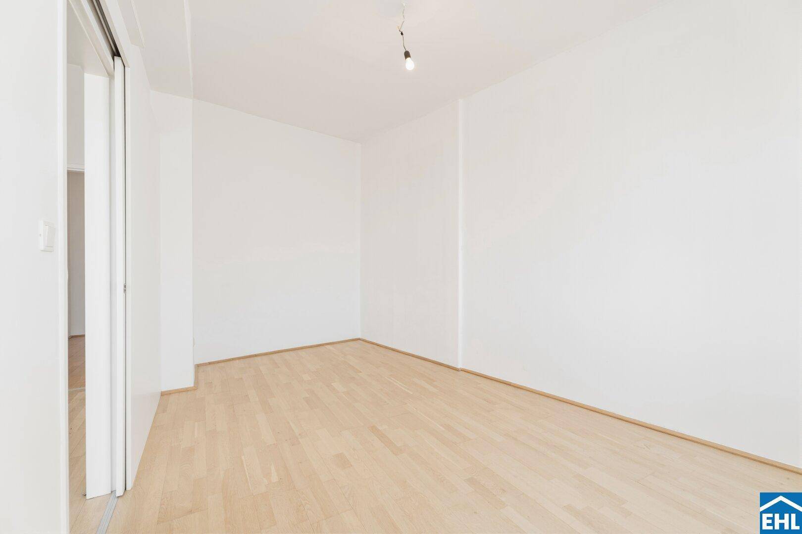 Helles Schlafzimmer mit Parkettboden und weiß gestrichenen Wänden, bietet eine ruhige Atmosphäre.