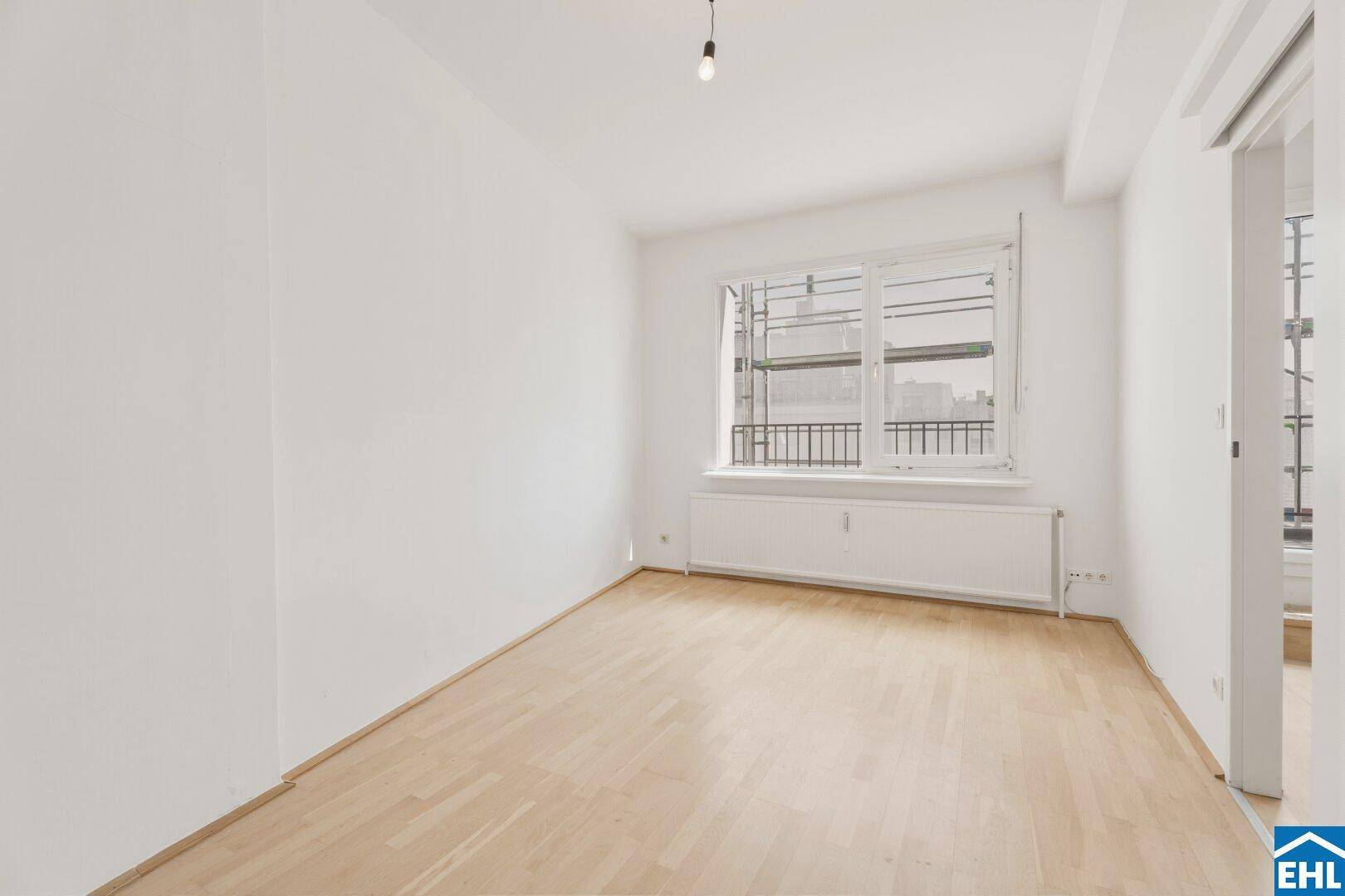 Ruhiges Schlafzimmer mit Parkettboden und Fenster, das eine helle und einladende Umgebung bietet.