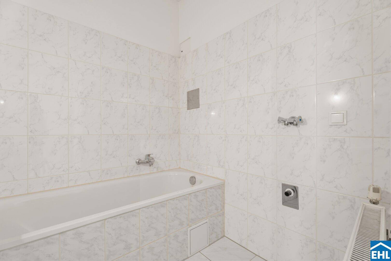 Funktionales Badezimmer mit Badewanne und weißen Fliesen, bietet eine saubere und helle Ästhetik.