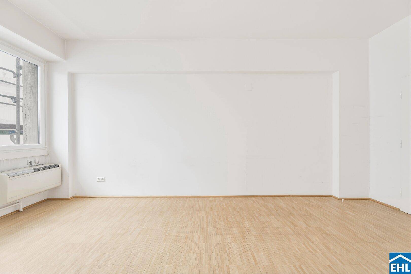 Leerer Wohnraum mit weißen Wänden und hellem Parkettboden, bietet eine neutrale Basis für neue Mieter.