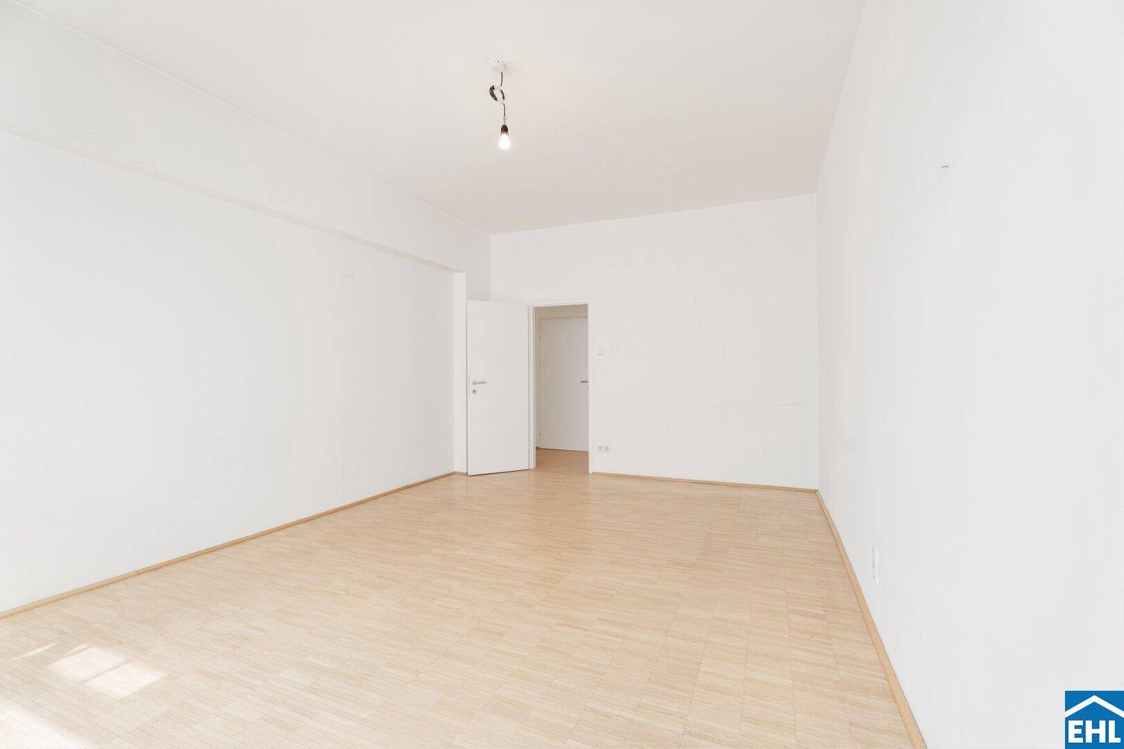 Heller Wohnraum mit Parkettboden und Zugang zu weiteren Zimmern, bietet eine flexible Raumaufteilung.