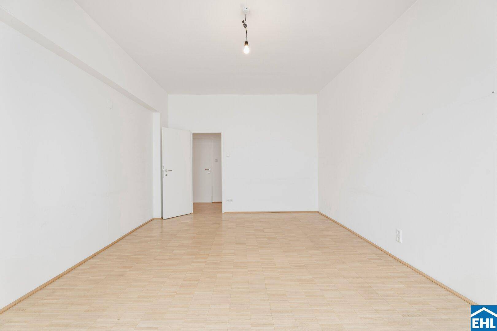 Geräumiger Wohnraum mit hellem Parkettboden und weiß gestrichenen Wänden, bereit zur individuellen Gestaltung.
