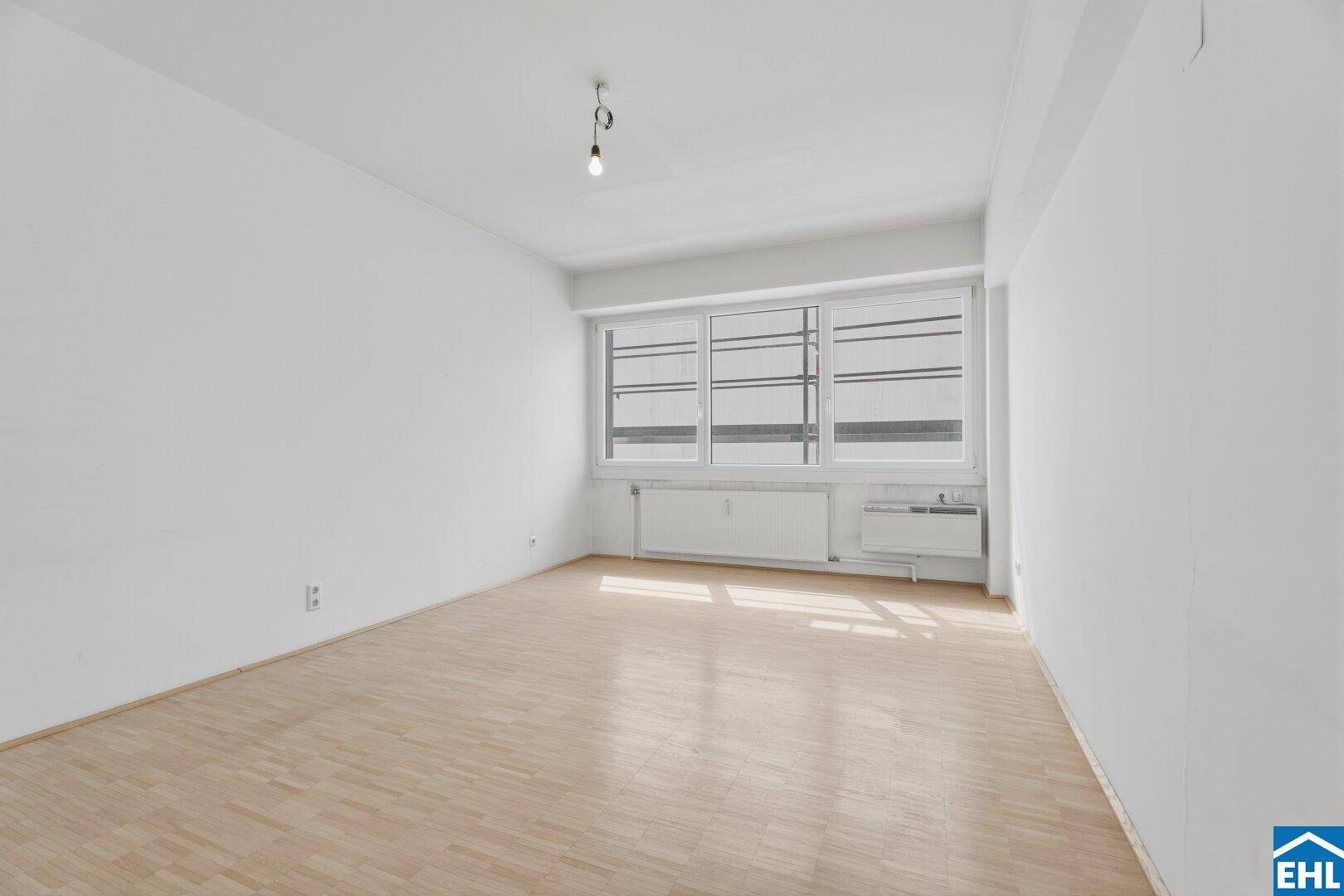 Lichtdurchfluteter Wohnraum mit großen Fenstern und hellem Parkettboden, ideal für modernes Wohnen.