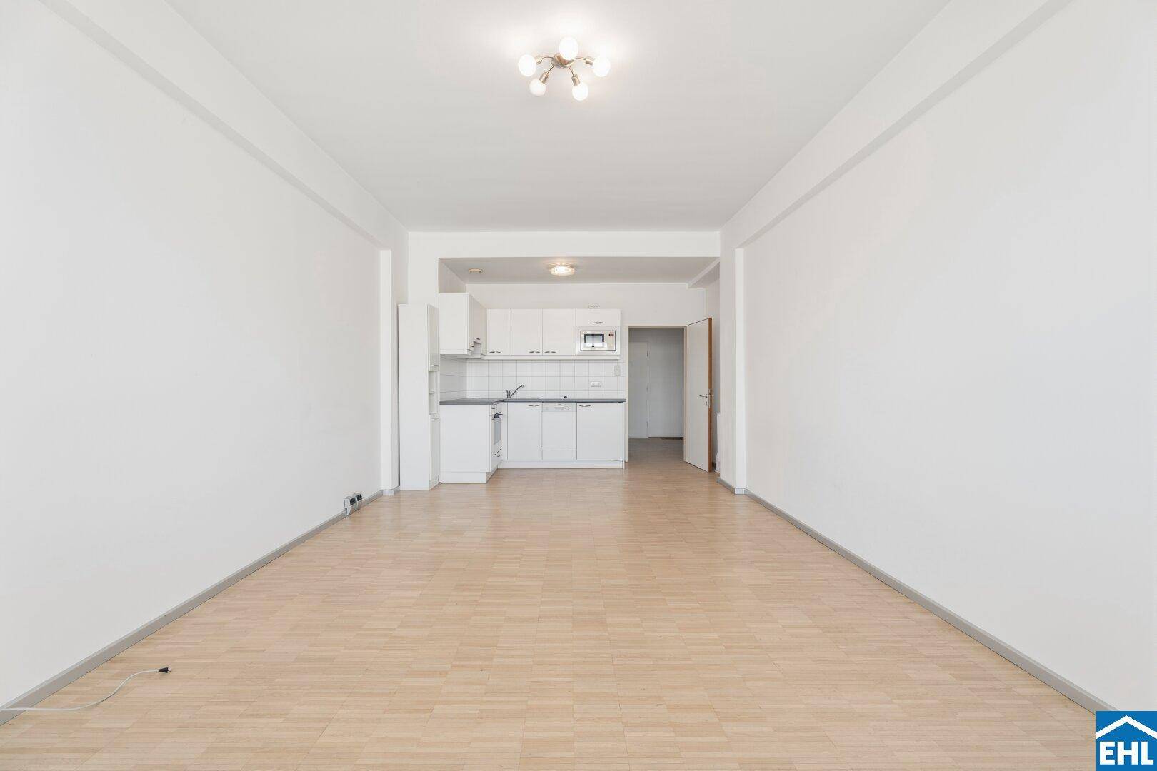 Heller Wohnbereich mit integrierter weißer Küchenzeile und Parkettboden, ideal für offenes Wohnen.
