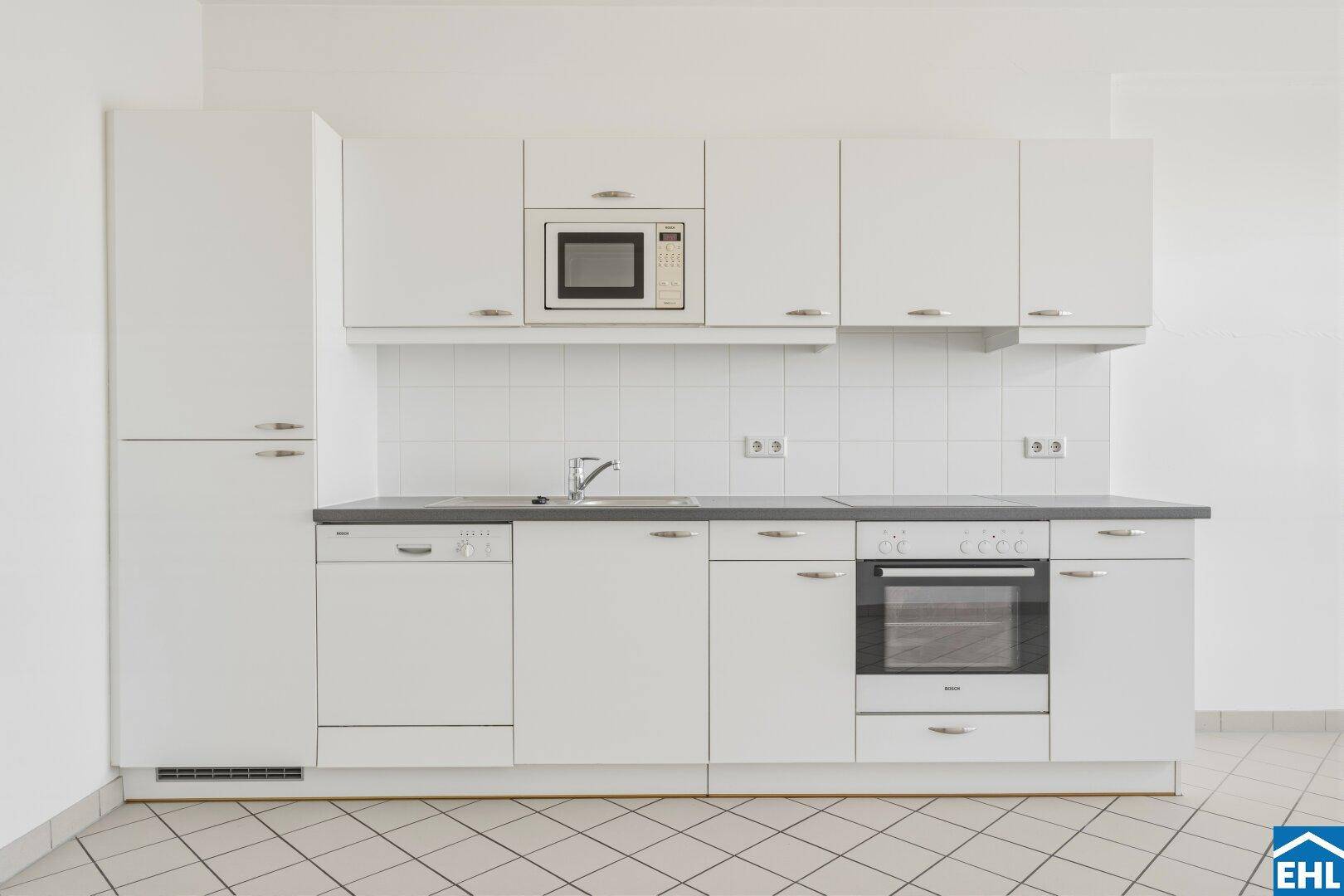 Funktionale Einbauküche in Weiß mit integriertem Backofen und Mikrowelle.