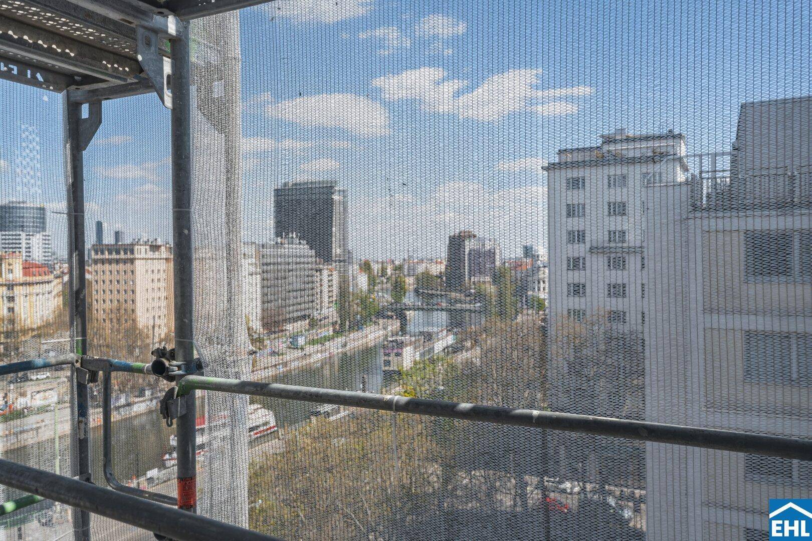 Weitblick über die Stadt mit Fluss und Gebäuden, teilweise durch Gerüst verdeckt.