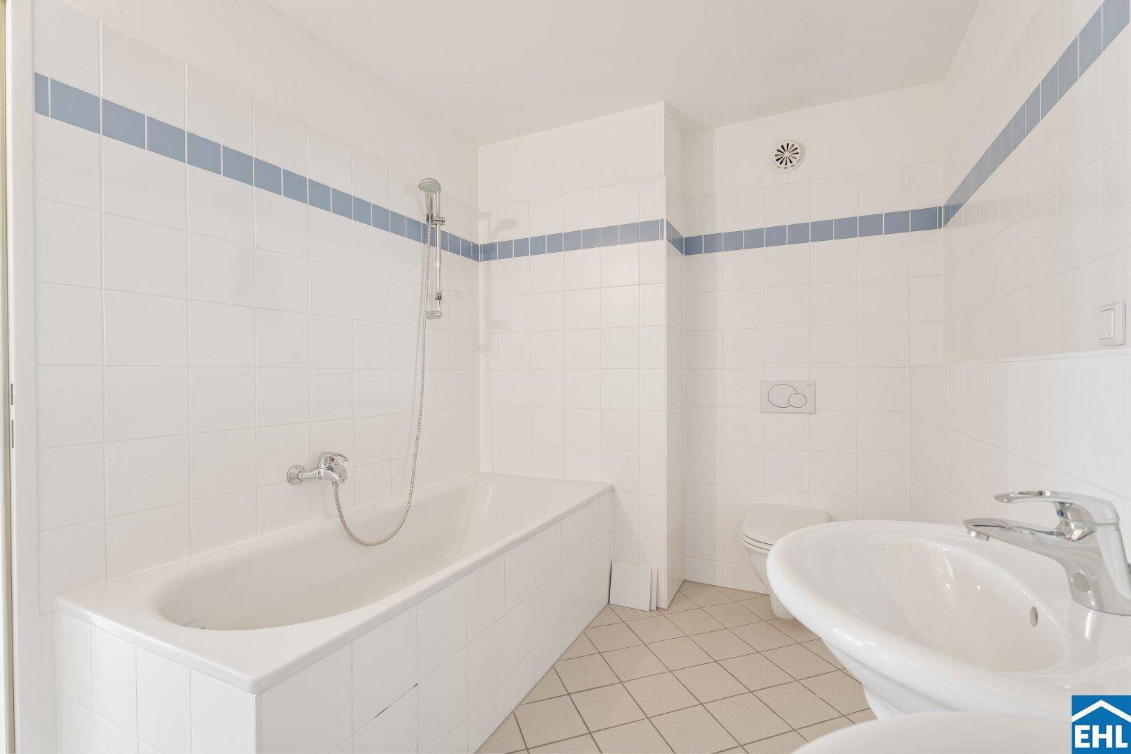 Badezimmer mit Badewanne, Wand-WC und weißen Fliesen.