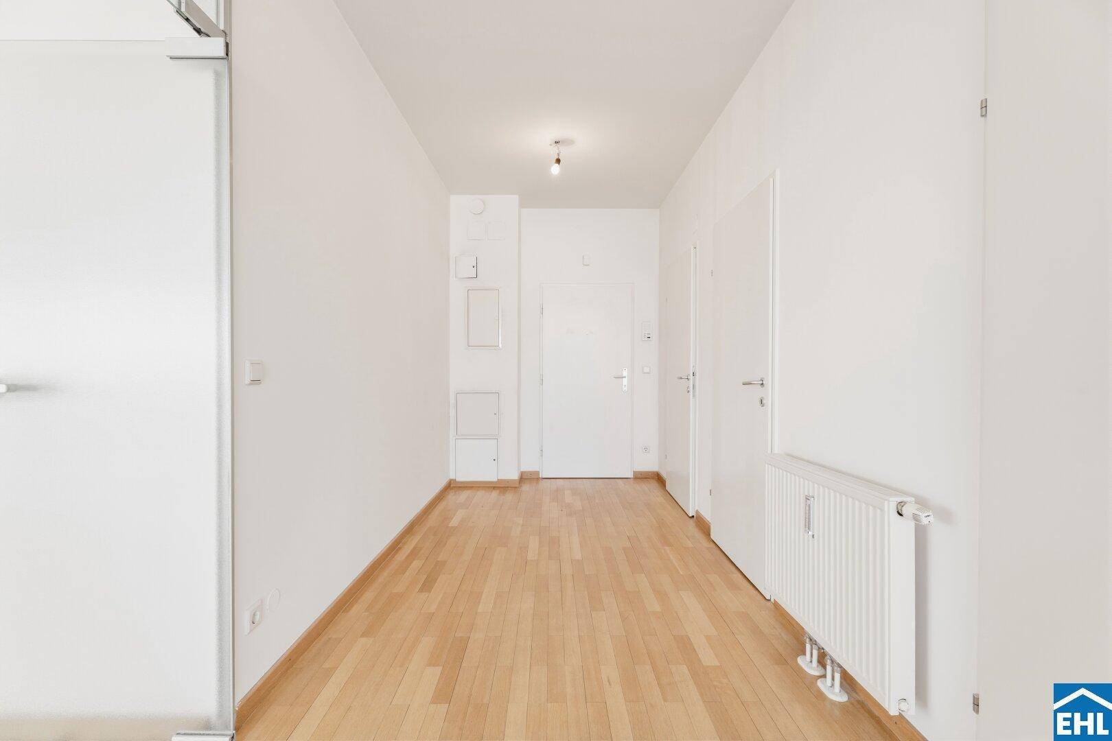 Langer, heller Flur mit Parkettboden und Zugang zu weiteren Räumen.