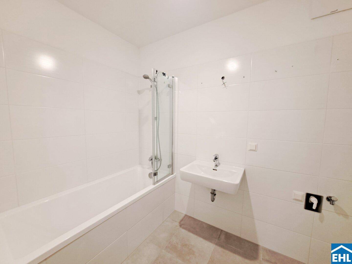Modernes Badezimmer mit Badewanne, Dusche und Waschbecken, komplett gefliest.