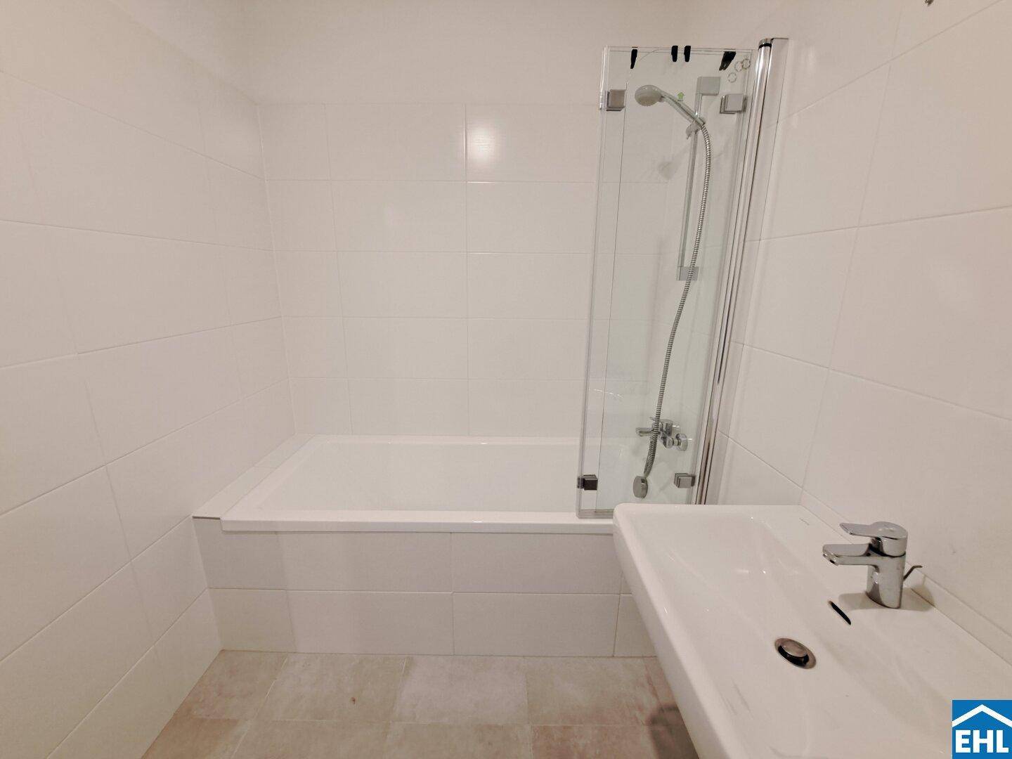 Helles Badezimmer mit Badewanne, Duschabtrennung und modernem Waschbecken.