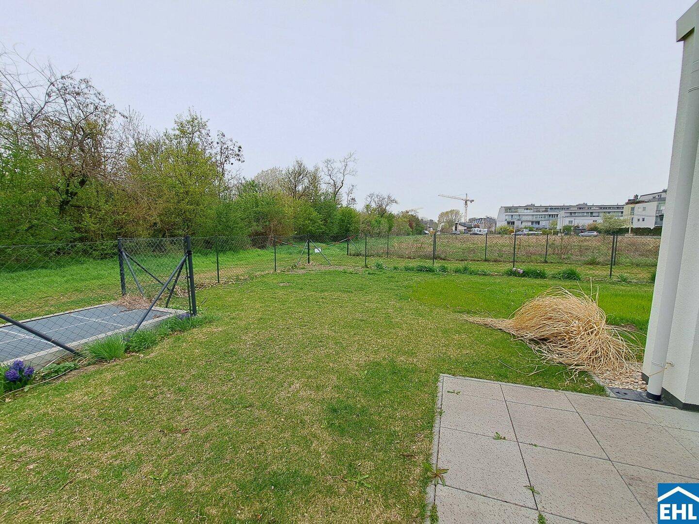 Weitläufiger Garten mit Rasen und Blick auf die Umgebung, inklusive einer kleinen Terrasse.