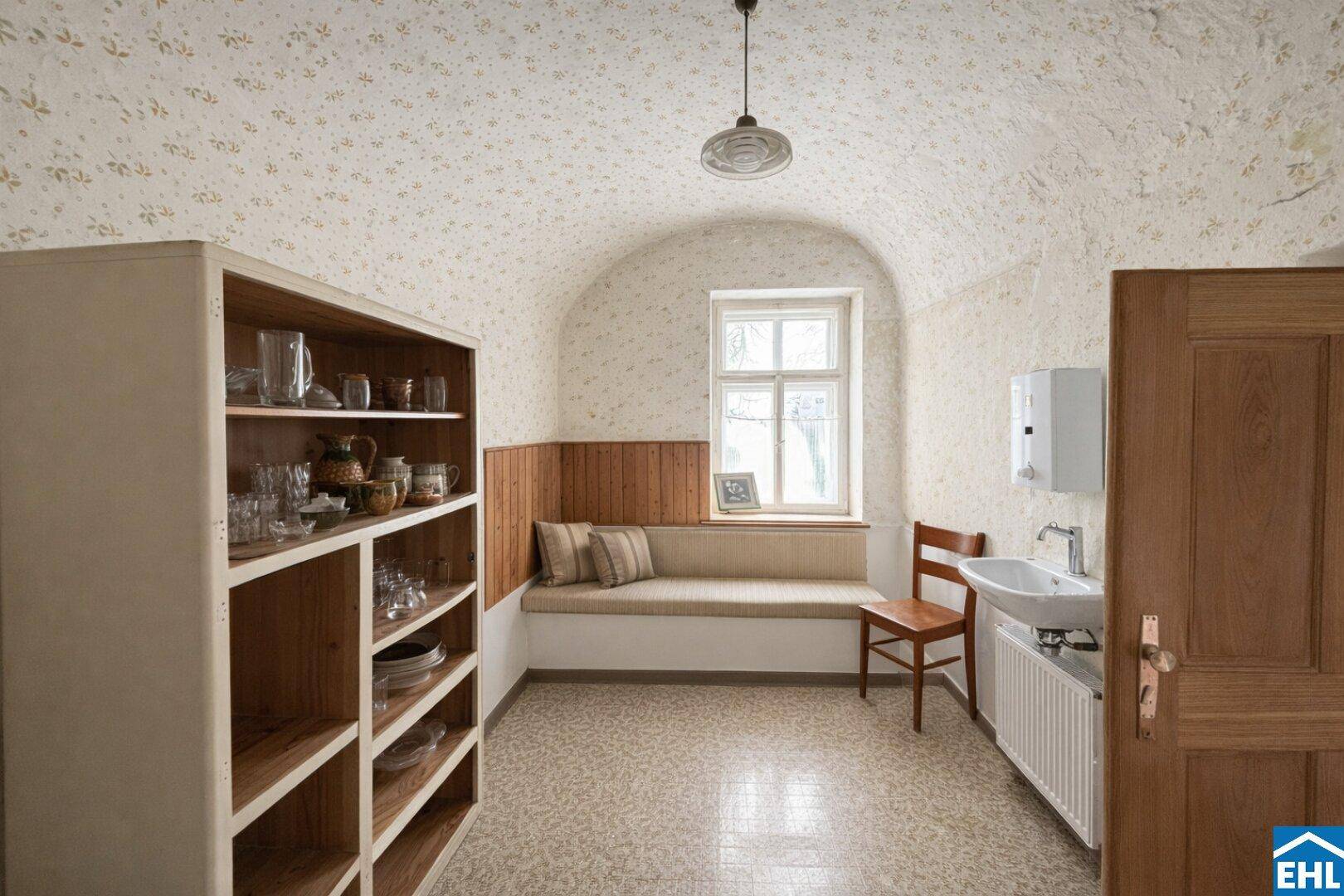 Praktischer Raum mit Gewölbedecke, Fensterbank, Waschbecken und Stauraum in einem Altbau.