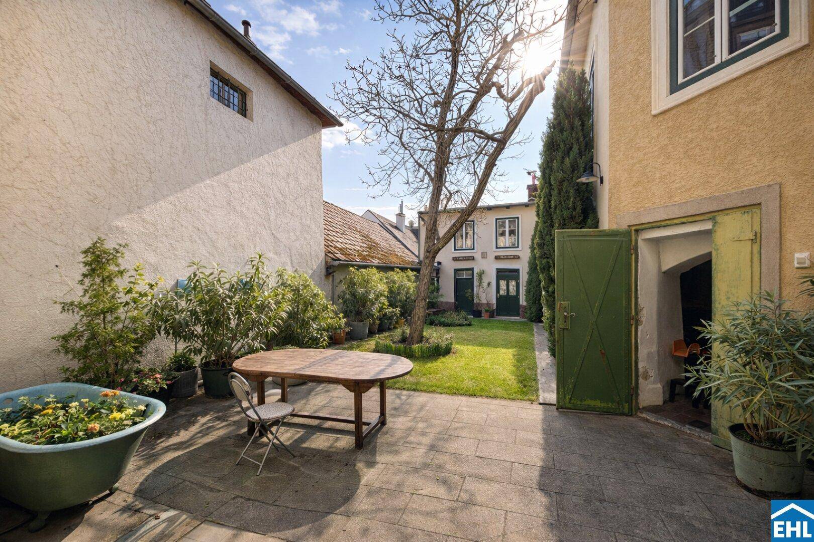 Sonniger gepflasterter Innenhof mit Sitzgelegenheiten und Blick auf die umliegenden Gebäude.