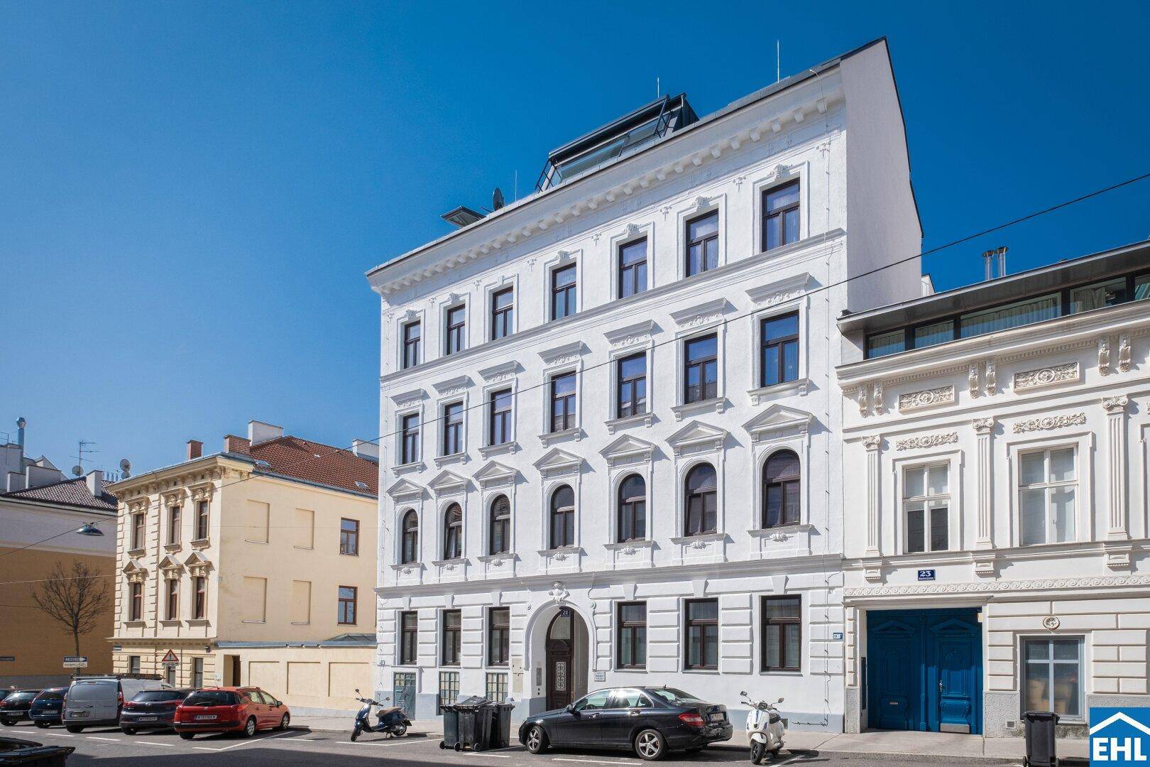 Historisches Gebäude mit weißer Fassade und vielen Fenstern unter blauem Himmel in der Stadt.