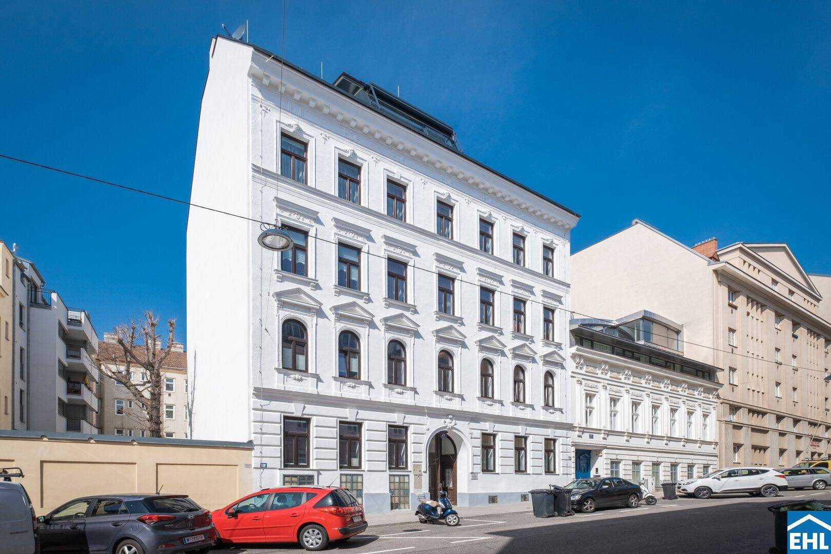 Elegantes Altbaugebäude mit weißer Fassade und klassischer Architektur in einer städtischen Umgebung.