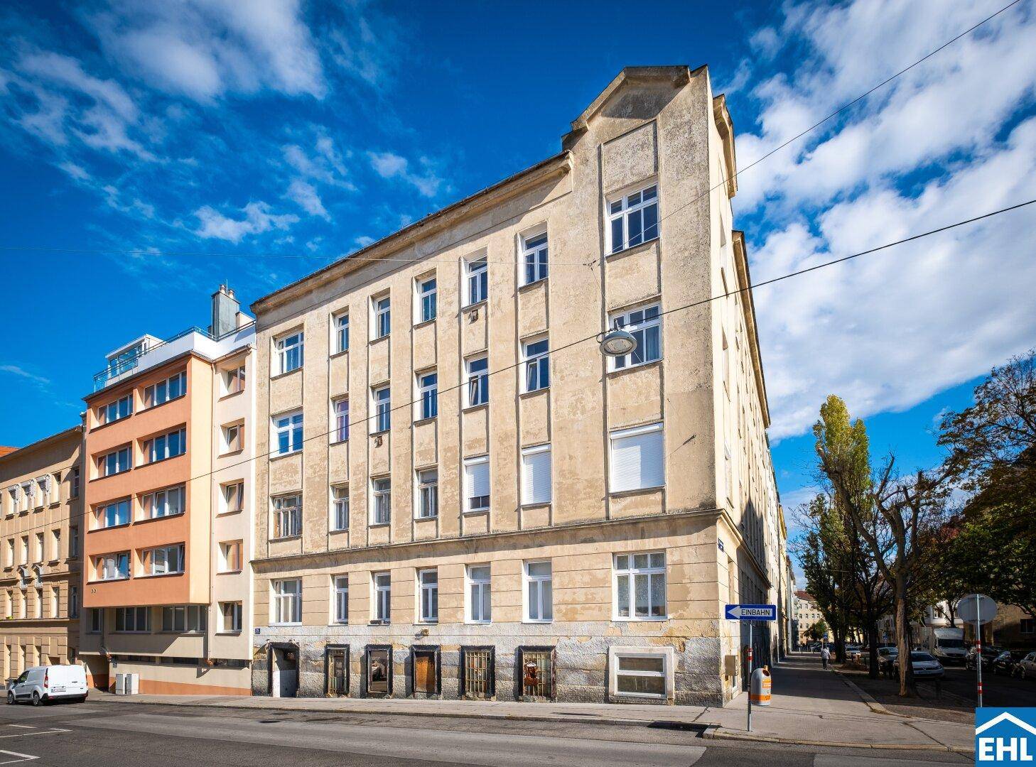 Ansicht eines älteren Wohnhauses mit einfacher Fassade und vielen Fenstern an einer belebten Straße.