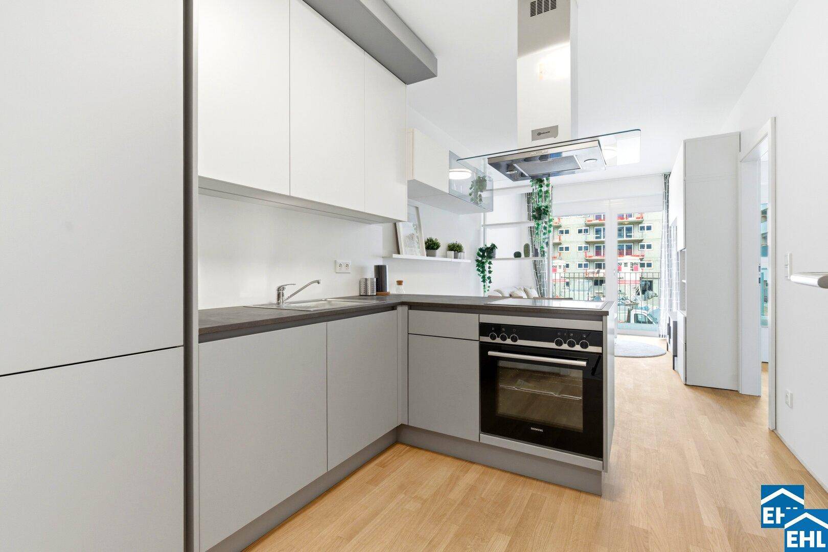 Helle Küche mit modernen grauen und weißen Schränken und Blick auf den Balkon.