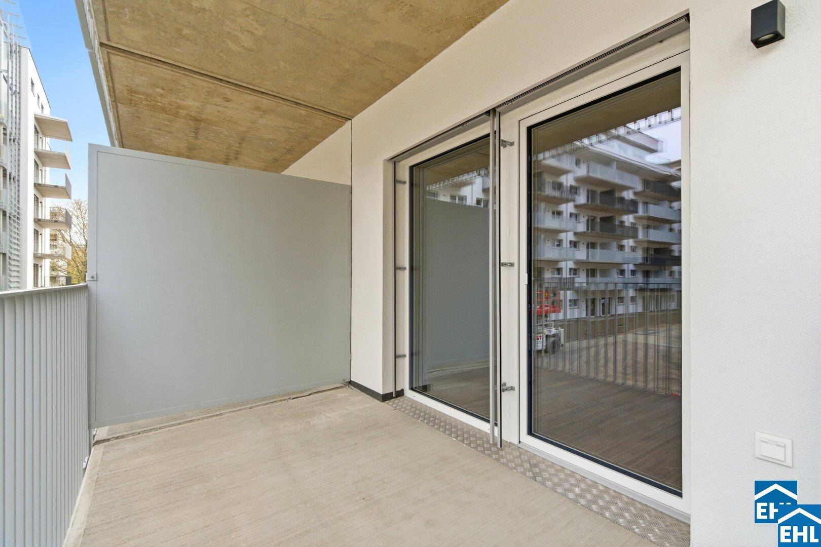 Geräumiger Balkon mit Betonboden und Blick auf die umliegenden Gebäude.