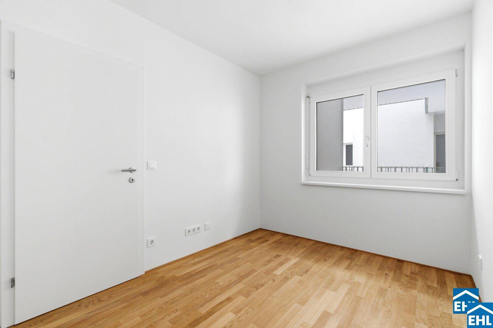 Leeres Zimmer mit Parkettboden und weißer Tür, bereit zur individuellen Gestaltung.