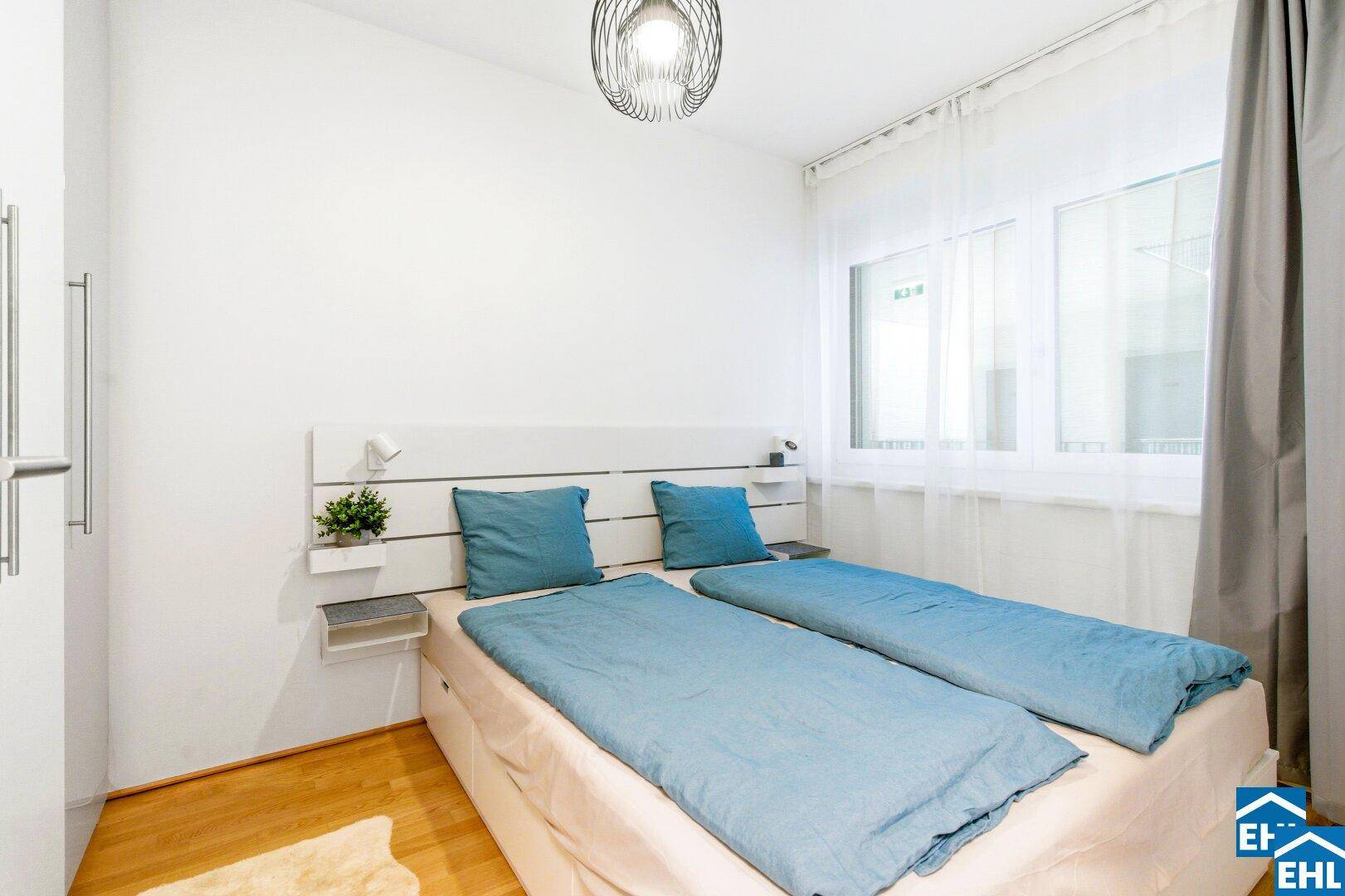 Modern eingerichtetes Schlafzimmer mit Doppelbett, Parkettboden und Fenster.