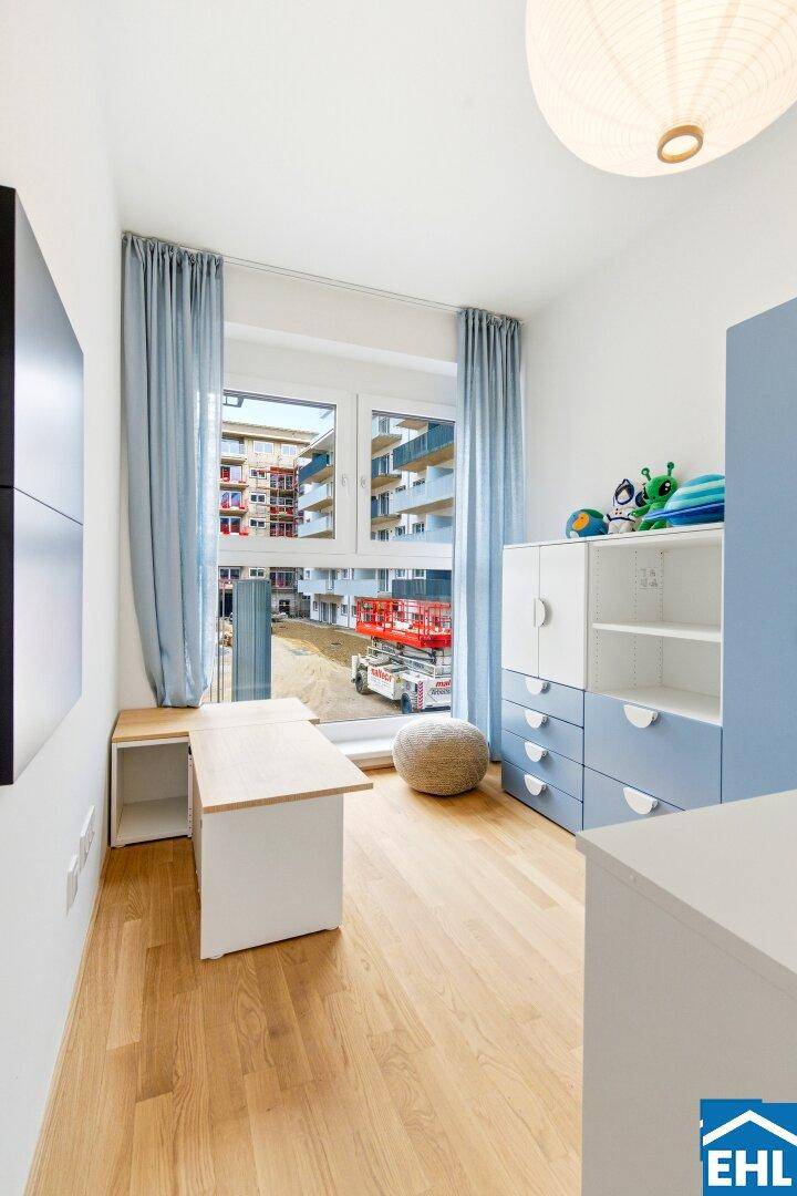 Kinderzimmer mit Schreibtisch, blauen Vorhängen und Parkettboden, hell und freundlich.