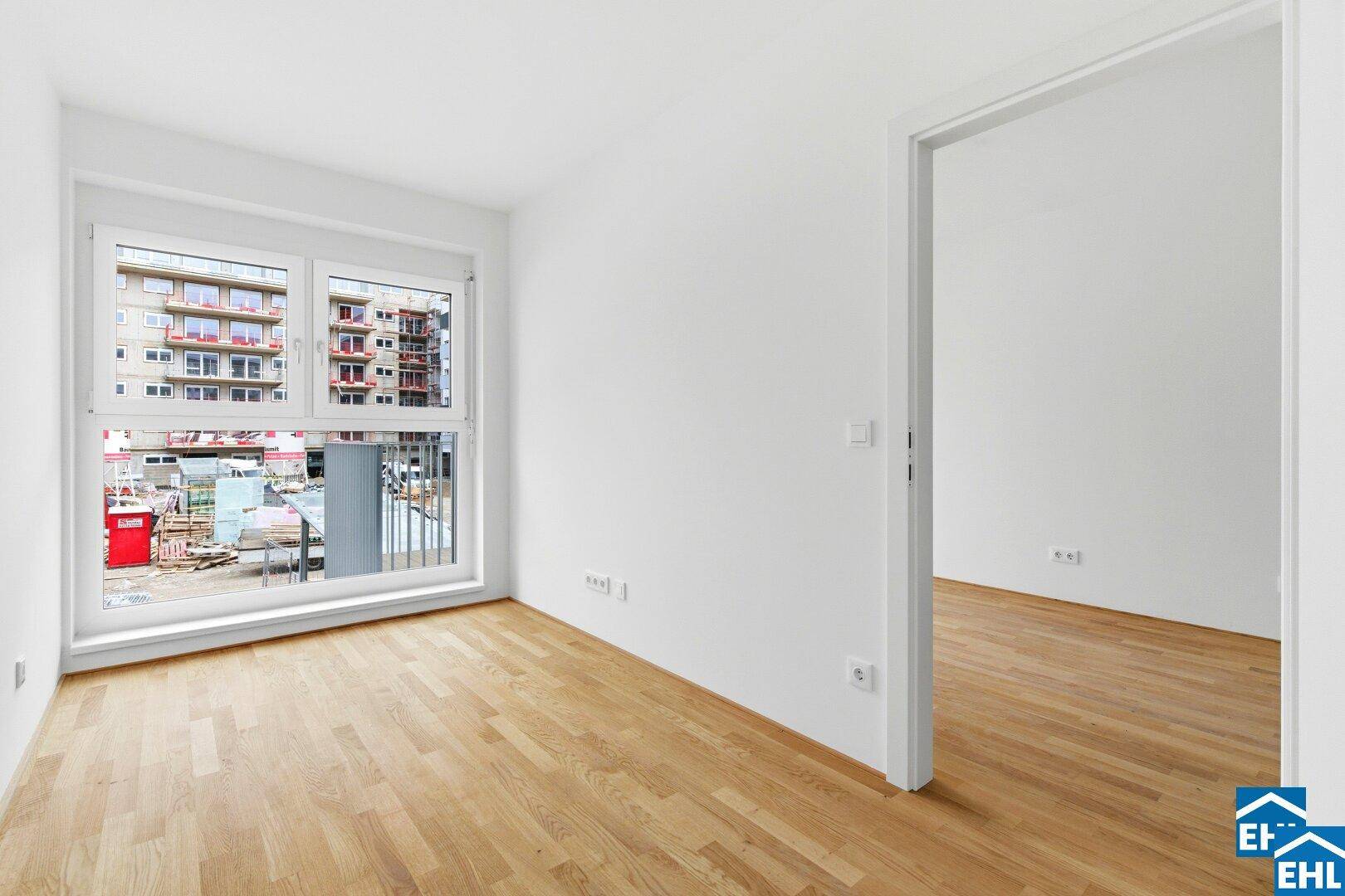 Leeres Zimmer mit Parkettboden und großem Fenster, ideal für Schlaf- oder Arbeitsbereich.