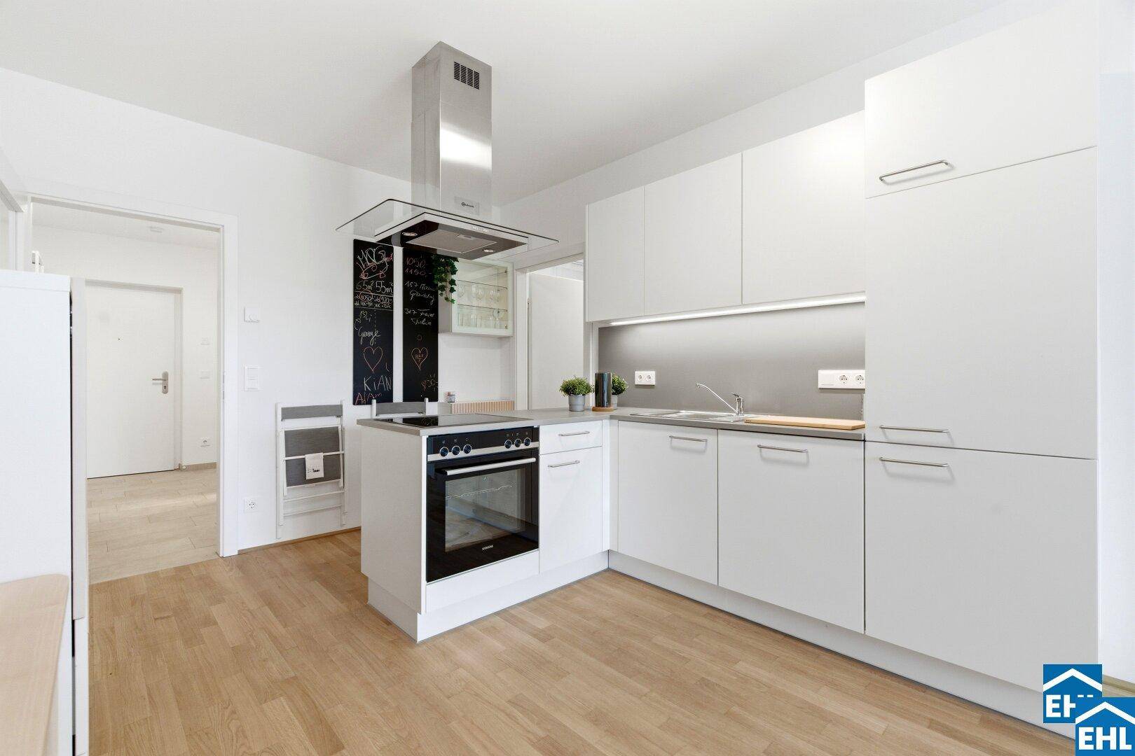 Moderne weiße Einbauküche mit Kochinsel, Backofen und Dunstabzugshaube.