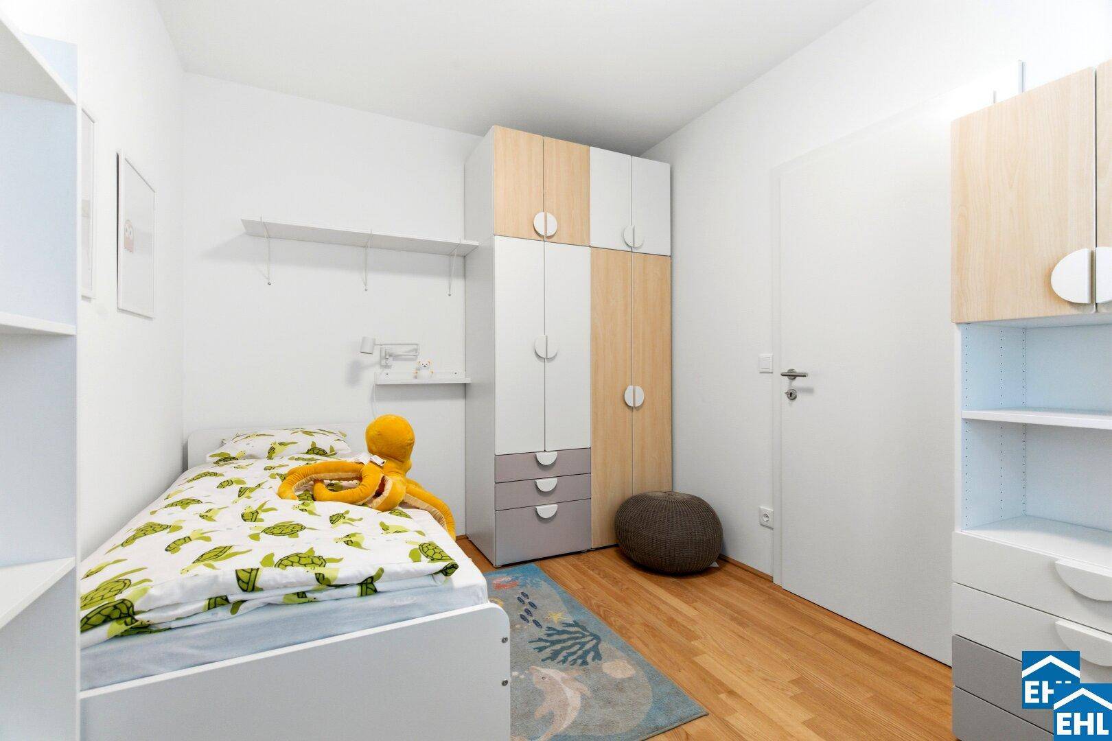 Helles Kinderzimmer mit Holzboden, Kleiderschrank und spielerischer Dekoration.