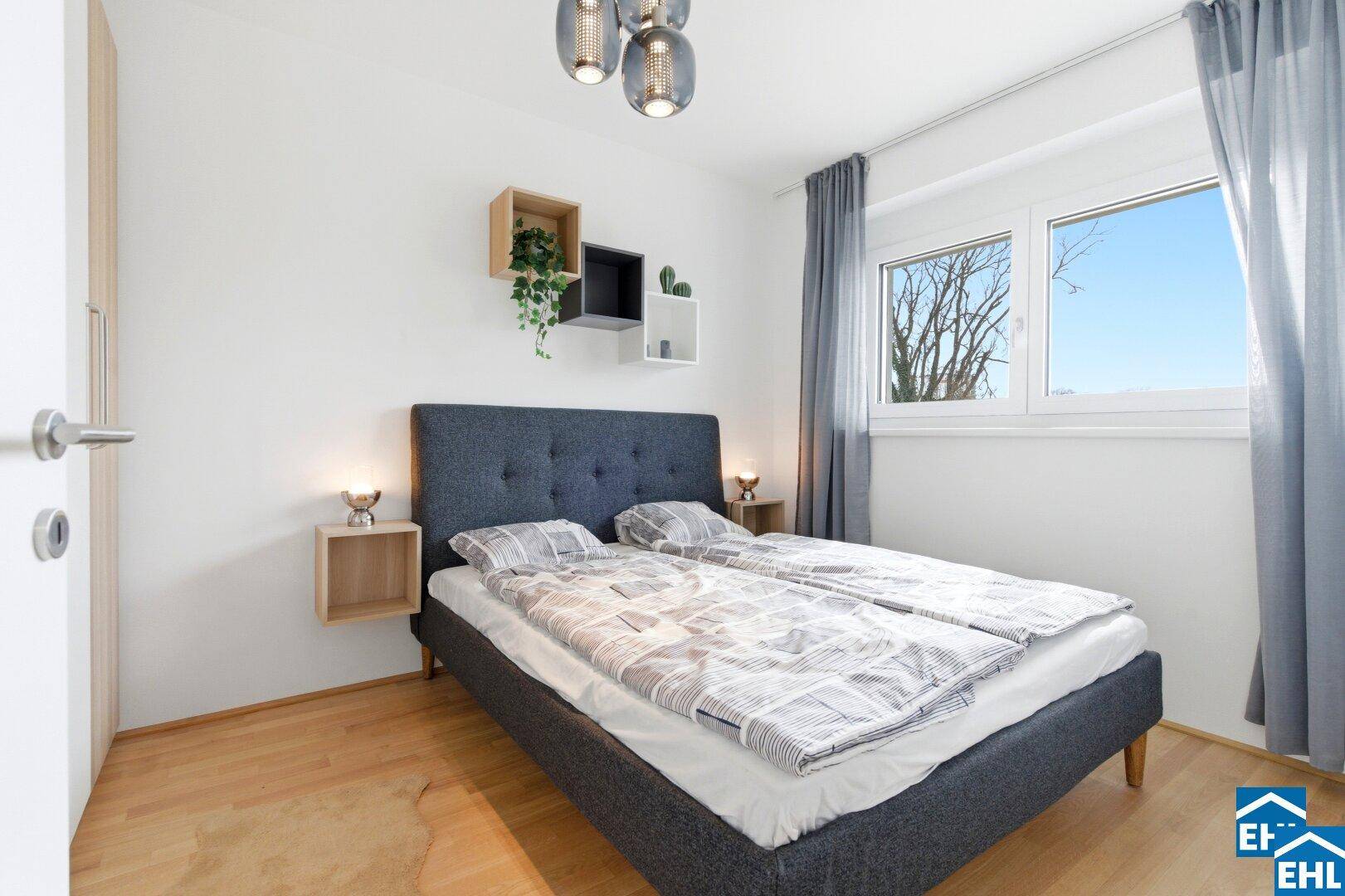 Schlafzimmer mit Doppelbett, Holzboden und großem Fenster für viel Tageslicht.