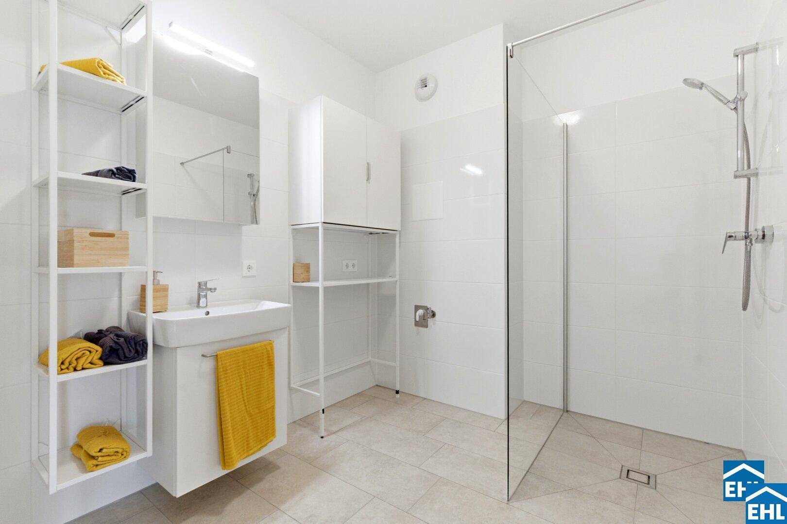 Modernes Badezimmer mit ebenerdiger Dusche, Waschbecken und weißen Fliesen.