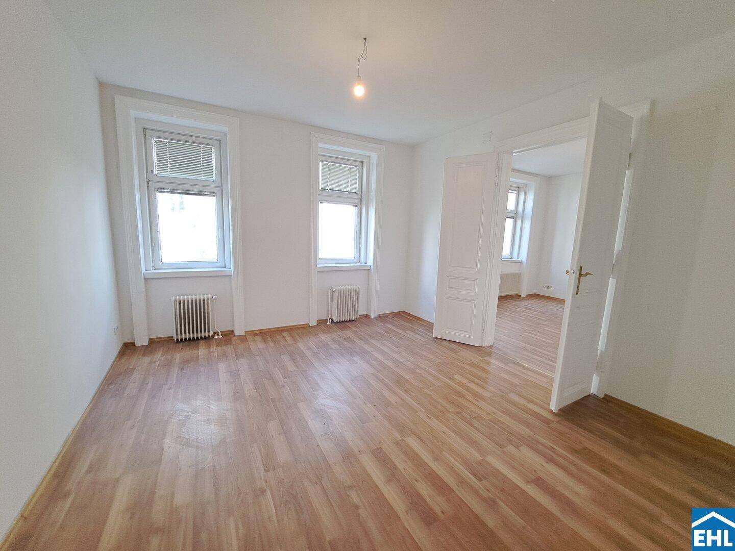 Geräumiges Zimmer mit Laminatboden und zwei Fenstern, die für eine angenehme Belichtung sorgen.